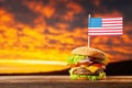 Close-up home made beef burger with american flag on the top on wooden table over sunset sky background Royalty Free Stock Photo