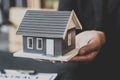 Close-up, a home salesman holding a gray miniature house model. Royalty Free Stock Photo