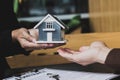 Close-up, a home salesman holding a gray miniature house model. Royalty Free Stock Photo