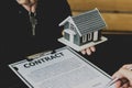 Close-up, a home salesman holding a gray miniature house model and house keys. Royalty Free Stock Photo