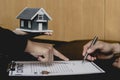 Close-up, a home salesman holding a small gray house model and pointing at the purchase contract. Royalty Free Stock Photo