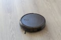 Close-up home vacuum cleaning robot in action on living room laminate wooden floor