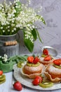 Close-up of homemade appetizing muffins, garnished with strawberries and kiwi on a wooden background. Vertical composition