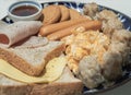 Close-up of Homemade breakfast is including Breads, Fried sausages, Ham, Pork shumais, Scrambled eggs, Cheese, Crispy ginger