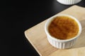 Close up homemade creme brulee in white ramekin  with sugar burn top up on black background with copy space. French dessert creme Royalty Free Stock Photo