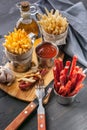 Close Up Homemade French Fries, Onions, Garlic, Smoked Sausages, Tomato Sauce, Fork and Spoon on Dark Wooden Table. Vertical shot Royalty Free Stock Photo
