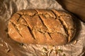 Close-up homemade fresh loaf of bread, pumpkin seeds on parchment paper on wooden table Royalty Free Stock Photo