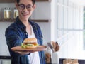 Close-up of a homemade hamburger on wooden dish holding by young man Royalty Free Stock Photo