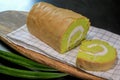 Close up of homemade Pandan Jam Roll Cake with white cream inside, on wooden board on black table background. Foods and drinks Royalty Free Stock Photo