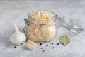 Close-up of homemade sauerkraut in a glass jar on a gray background, next to a head of garlic, black pepper and bay leaf. Royalty Free Stock Photo