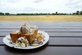 Close up of honey toast with ice cream, chocolate, whip cream and cereal topped with honey on the wooden table.