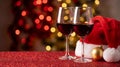 Holiday Red Wine Glasses and Santa Hat on Glitter Surface Royalty Free Stock Photo