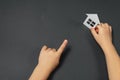 Close up horizontal image of child`s hands holding white paper house on gray background. Family home and real estate concept. Royalty Free Stock Photo