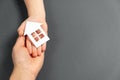 Close up horizontal image of female and child hands holding white paper house on gray background. Royalty Free Stock Photo