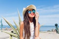 Close-up horizontal portrait of attractive brunette girl with long hair sitting on the beach near cactus on the Royalty Free Stock Photo