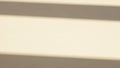 Close up of horizontal shadow lines cast by blinds on a pale beige wall creating a minimalist and abstract pattern of light and Royalty Free Stock Photo