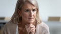 Pensive mature woman feels stressed lost in thoughts sitting indoors Royalty Free Stock Photo