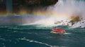 Close up of The Hornblower cruise boat traveling under a rainbow in front of the American Falls