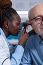 Close up of hospital specialist examining retired man using otoscope Royalty Free Stock Photo