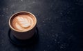 Close up hot capucino coffee cup with latte art foam on black stone table at cafe.dark scene.banner space mock up for adding text