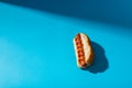 Close-up of hot dog with mustered and tomato sauce against blue background with copy space