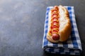 Close-up of hot dog with tomato and mustered sauce on checked pattern napkin at table