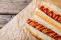 Close-up of hot dogs with mustered and tomato sauce served on brown wax paper at table