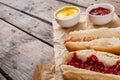 Close-up of hot dogs with tomato and mustered sauces on paper bags at table