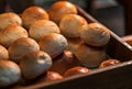 Close-up hot Fresh Baked Bread Rolls in a wooden box for the customer, the stack of freshly baked bread rolls, warm light from