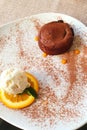 Close up of hot melting chocolate cake dessert and scoop of vanilla ice cream on orange slice on white plate. Chocolate fondant Royalty Free Stock Photo