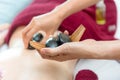 Close up hot stone lying down on skin back woman.  Asian beauty woman lying down on massage bed with traditional hot stones along Royalty Free Stock Photo