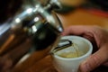 Close up hot tea pouring into a white cup. Blurry lights on black background. Pouring tea into cup from teapot