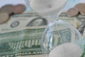 Close-up of hourglass on dollar money background - Concept of countdown, deadline and time is money