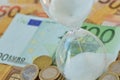 Close-up of hourglass on euro money background - Concept of countdown, deadline and time is money