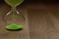 Close-up, hourglass with green sand on a wooden background