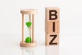 Close-up of an hourglass next to wooden blocks with the text BIZ