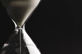 Close up of hourglass with white sand and copy space on black background