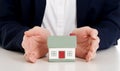 Close up on house model between hands on table. Royalty Free Stock Photo