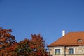 Close up of a house with red tiled roof. Cloudless clear blue sky background. Golden autumn tree foliage on the left Royalty Free Stock Photo