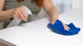 Close up of housekeeper cleaning white table, sanitizing table surface with disinfectant antibacterial spray bottle Royalty Free Stock Photo