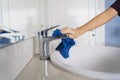 Housemaid cleaning faucet and sink by using rag