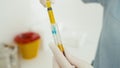 A close-up of how a doctor collects plasma from a test tube into a syringe.