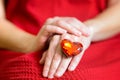 Close-up of a huge heart shaped fake gem ring on a woman`s hand wearing a red dress Royalty Free Stock Photo