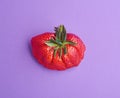 Close-up on a huge ugly strawberry on violet background