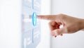 Close up of a human finger pressing a glowing blue button on a modern digital interface panel Royalty Free Stock Photo