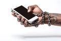 close-up of a human hand chained to a cell phone representing the excessive use of technologies, white background