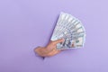 Close up of human hand holding fan of cash money in dollar banknotes, isolated through torn purple background, copy space for