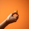 Hand Holding Crispy Fried Chicken Nugget Piece on Orange Background, Generated AI Royalty Free Stock Photo
