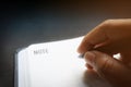 Close up human hands with black pen writing something on blank line notebook with black desk background in dramatic lighting tone. Royalty Free Stock Photo