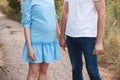 Close up of human hands holding pregnant belly, closeup happy family awaiting baby, standing on green grass, body part, young fami Royalty Free Stock Photo